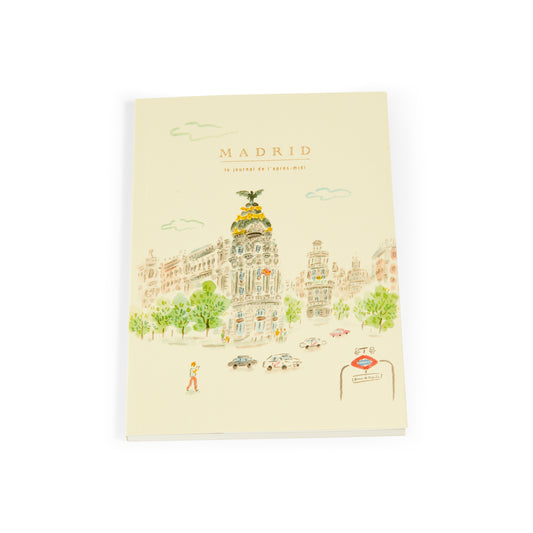 Cuaderno con portada ilustrada de edificio Metropolis Madrid y entrada de metro, fondo claro