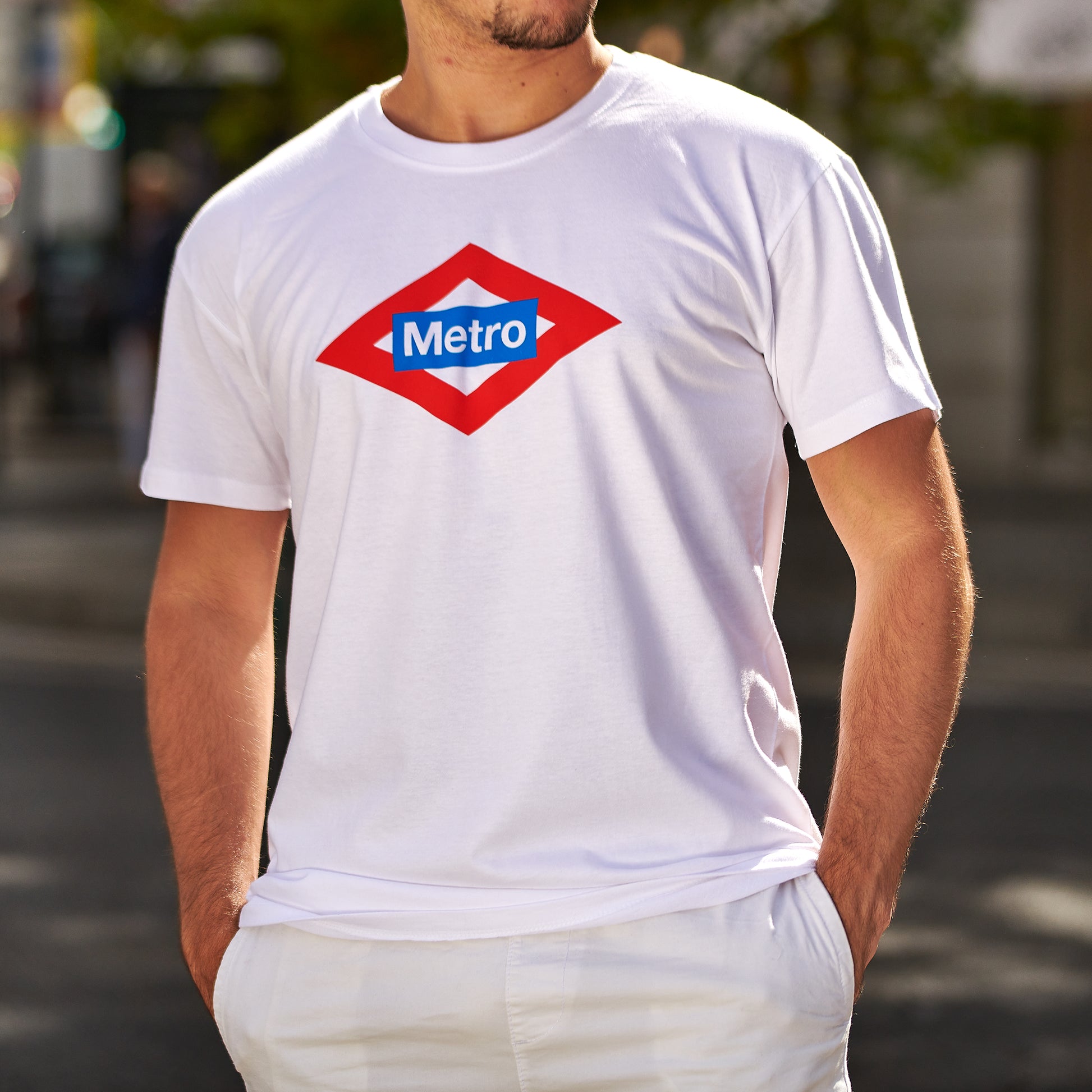 Hombre con camiseta blanca de logo Metro Madrid, moda urbana en exterior