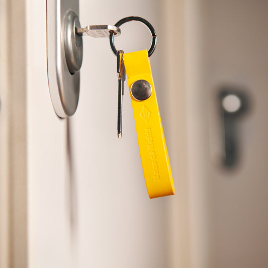 Llave con llavero amarillo colgada en cerradura de puerta, accesorio hogar seguro