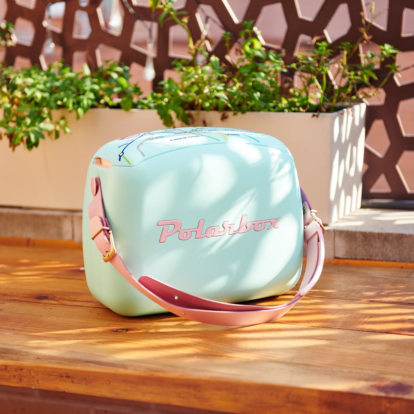 Nevera portátil Polarbox 6L color menta con correa rosa sobre mesa de madera al aire libre