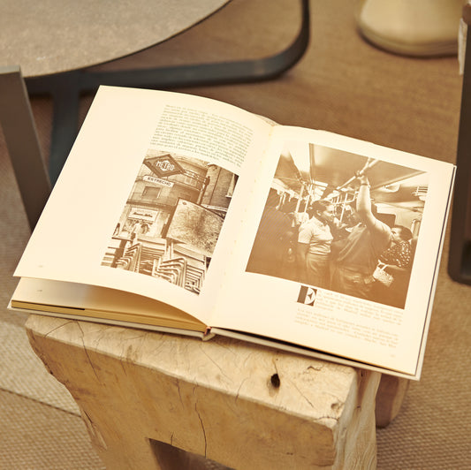 Libro abierto sobre mesa de madera mostrando fotos antiguas del metro y pasajeros en tren.