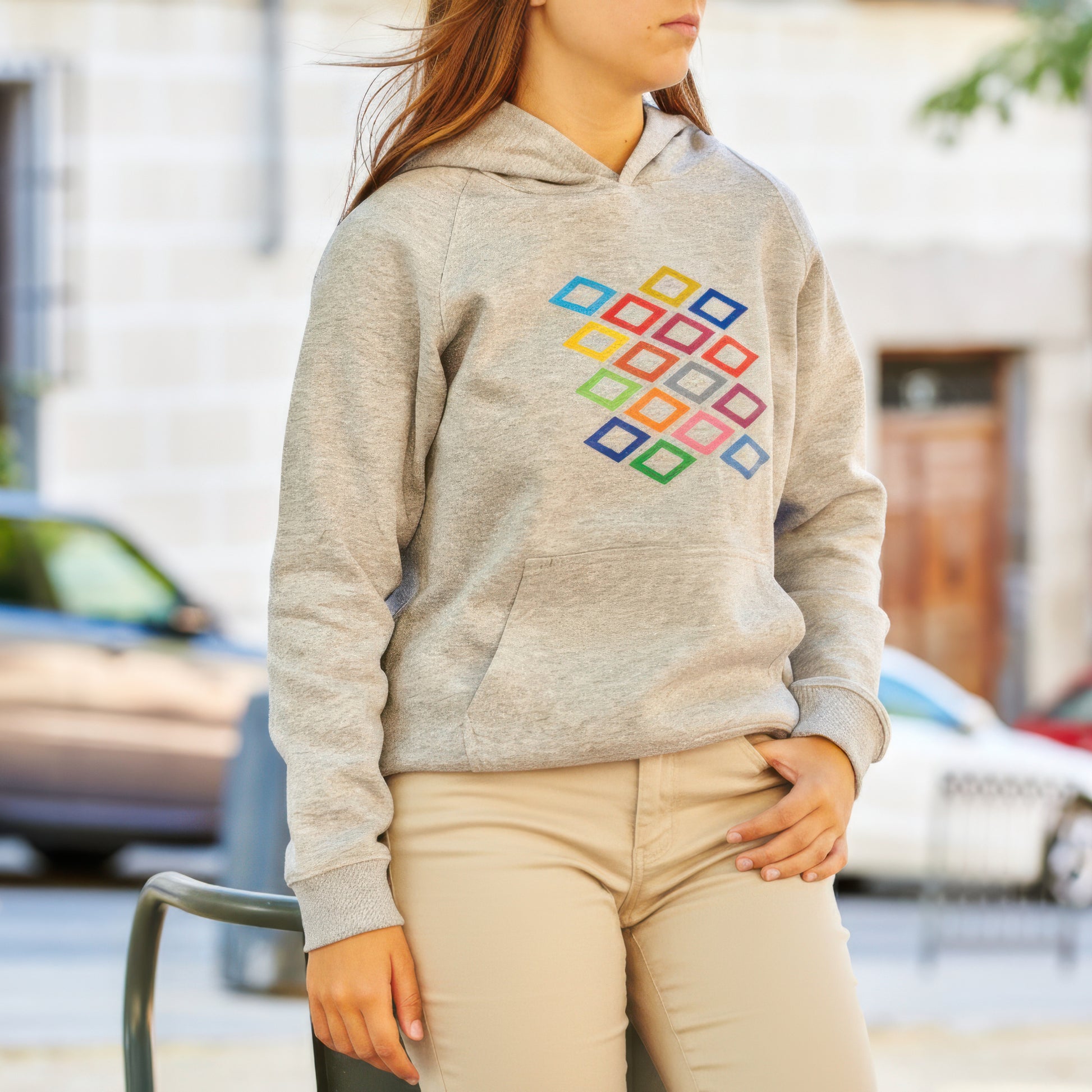 Mujer con sudadera gris con estampado de rombos de colores, sentada al aire libre