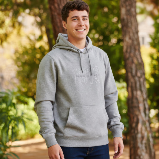 Joven con sudadera gris con capucha y estampado 1919, al aire libre en un parque